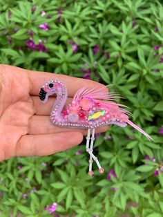 a pink flamingo brooch sitting on top of a hand