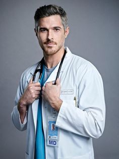 a male doctor in a white coat and blue tie is posing for the camera with his stethoscope