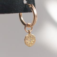 The Oriana gold huggie hoop earrings are a beautiful, delicate addition to anyone's accessory game. The hoops are approx. 15mm and gold filled, suitable for sensitive skin. The charms are approx. 8mm and gold vermeil with a brushed finish, and a stamped star is accented with a tiny CZ stone. 14k gold filled hoops, suitable for sensitive skin Brushed gold vermeil starburst charm Dainty 14k Gold Filled Huggie Cartilage Earrings, Dainty 14k Yellow Gold Filled Huggie Earrings, Everyday Yellow Gold Earrings With Star Charm, Everyday 14k Gold Jewelry With Star Charm, 14k Gold Filled Huggie Jewelry With Dangling Charms, Single 14k Gold Filled Huggie Earring For Gift, Dainty 14k Gold-filled Huggie Cartilage Earrings, Everyday Yellow Gold Huggie Earrings With Charms, Recycled Gold Huggie Earrings