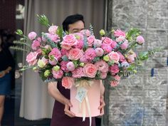 a man holding a large bouquet of pink flowers