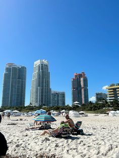 people sitting on the beach in front of high rise buildings