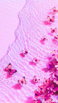 pink flowers and butterflies are floating in the water on top of a sandy beach with waves