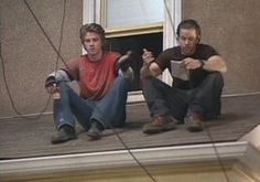 two men sitting on the roof of a house