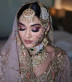 a woman in a bridal outfit with jewelry on her head and veil over her face