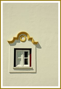 a white building with a window and gold trim