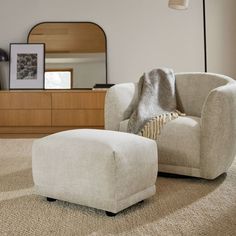 a chair and ottoman in a living room with a mirror on the wall behind it