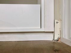 an open white door with wood flooring next to it and a cat peeking out