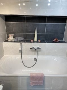 a white bath tub sitting under a window next to a sink and toilet paper roll