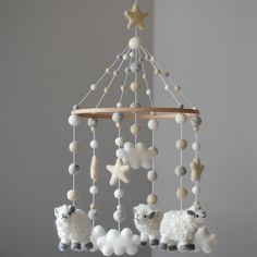 a crib mobile with sheep and stars hanging from it's sides in a room