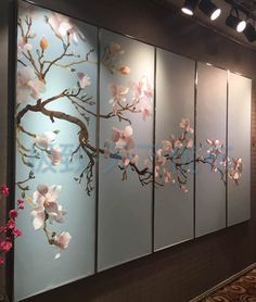 four panels with flowers on them are hanging from the ceiling in front of a wall