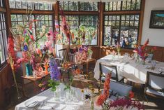 an indoor dining area with tables and chairs covered in white tablecloths surrounded by flowers