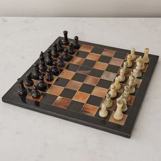 a black and white chess set on a marble board with pieces arranged in the shape of squares