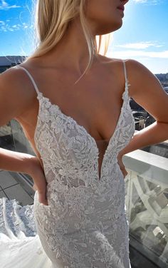 a woman in a white wedding dress standing on a balcony with her back to the camera