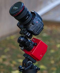 a camera mounted on top of a tripod with a lens attached to it's holder