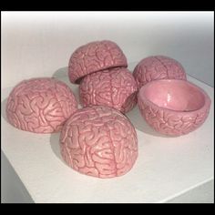 four pink brain bowls sitting on top of a white surface