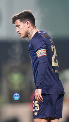 a soccer player with tattoos on his face and chest standing in front of the ball