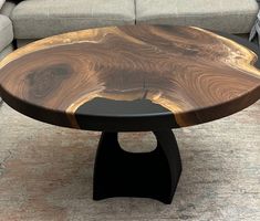 a coffee table made out of wood with black legs and an abstract design on the top