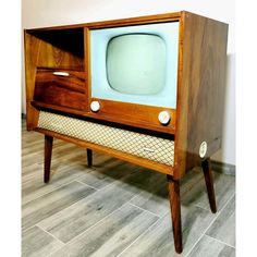 an old fashioned tv sitting on top of a wooden stand in front of a wall