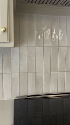 a black stove top oven sitting in a kitchen next to a white tiled backsplash