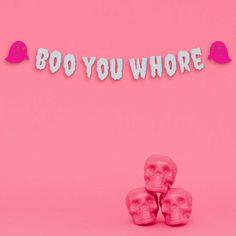 three pink skulls are sitting in front of a sign that says boo you who?