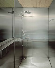 an empty bathroom with glass walls and stainless steel fixtures