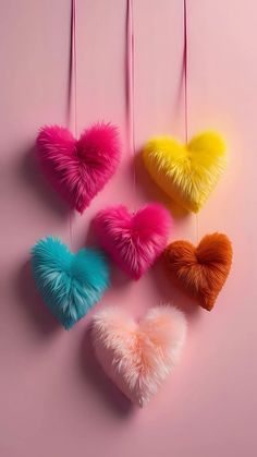 four hearts hanging from strings on a pink background