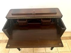 a wooden desk with two drawers on wheels and one drawer open to show the contents