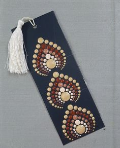 a bookmark decorated with circles and tassels on a gray background, hanging from a string