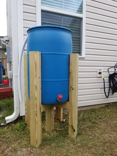 a large blue water tank sitting on top of a wooden stand next to a house