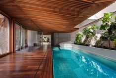 an indoor swimming pool surrounded by wooden flooring and walls with plants on either side