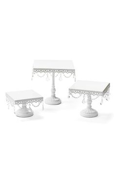 three white tables sitting next to each other on top of a white table covered in beads