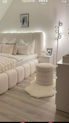 a white bed sitting in the middle of a bedroom next to a lamp and pictures on the wall