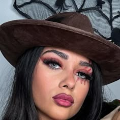 a woman wearing a brown hat with red makeup on her face and eyeliners