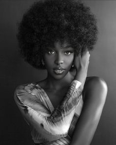 a woman with an afro is posing for a black and white photo, she has her hand on her head