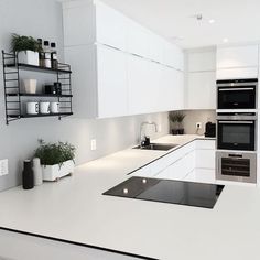 a kitchen with white cabinets and black counter tops, pots on the shelf above the stove