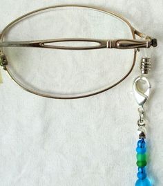 Light Blue Beaded Eyeglass Chain 26.5" in length, made with glass beads, beading cord, metal lobster clasps, and adjustable rubber holders. Lobster clasps make it easy to change the rubber holders, and an extra pair of holders are included with every purchase. You can convert this eyeglass chain into a convenient mask chain as well! Simply remove the rubber holders from the lobster clasps, and replace them with face mask straps, as shown. You'll never mis-place your mask again, and always have i Adjustable Metal Beaded Necklace With Lobster Clasp, Adjustable Blue Beaded Necklace With Lobster Clasp, Blue Adjustable Glasses Chain For Summer, Bohemian Blue Beaded Glasses Chains, Blue Glass Glasses Chains With Colorful Beads, Adjustable Silver Beads With Lobster Clasp, Elegant Blue Adjustable Glasses Chains, Blue Beaded Glass Glasses Chains, Silver Adjustable Beads With Lobster Clasp