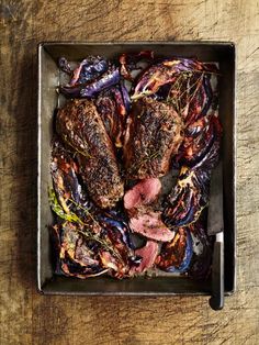 some meat and vegetables in a pan on a wooden table