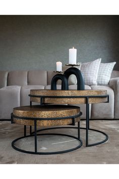 three tables with candles on them in front of a couch