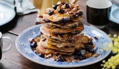 a stack of pancakes sitting on top of a blue plate next to a cup of coffee