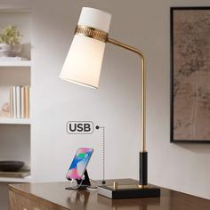 a desk lamp sitting on top of a wooden table next to a phone and charger