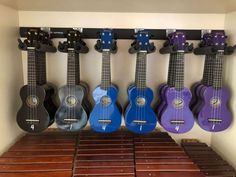 several ukuleles are lined up in a row on the wall next to each other