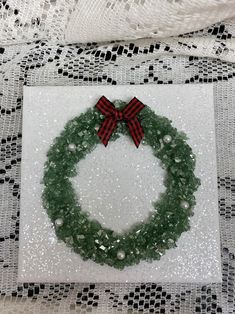 a green wreath with red bow on top of a white plate covered in sequins