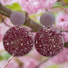 the earrings are made from glass and have pink speckles on them, along with silver discs