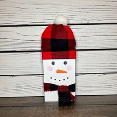 a wooden snowman with a red and black plaid hat on it's head