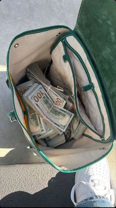 a bag filled with money sitting on top of a cement floor next to someone's feet