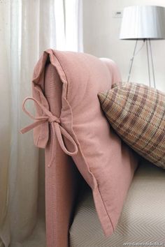 a pink couch with two pillows tied to it's back and one pillow on the other side