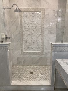 a white marble bathroom with two sinks and a walk in shower