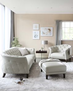 a living room with two white chairs and a footstool in front of a window