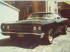 an old black car parked in front of a house