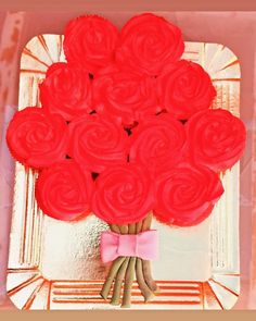 a bouquet of red roses in front of a mirror with a pink bow on it